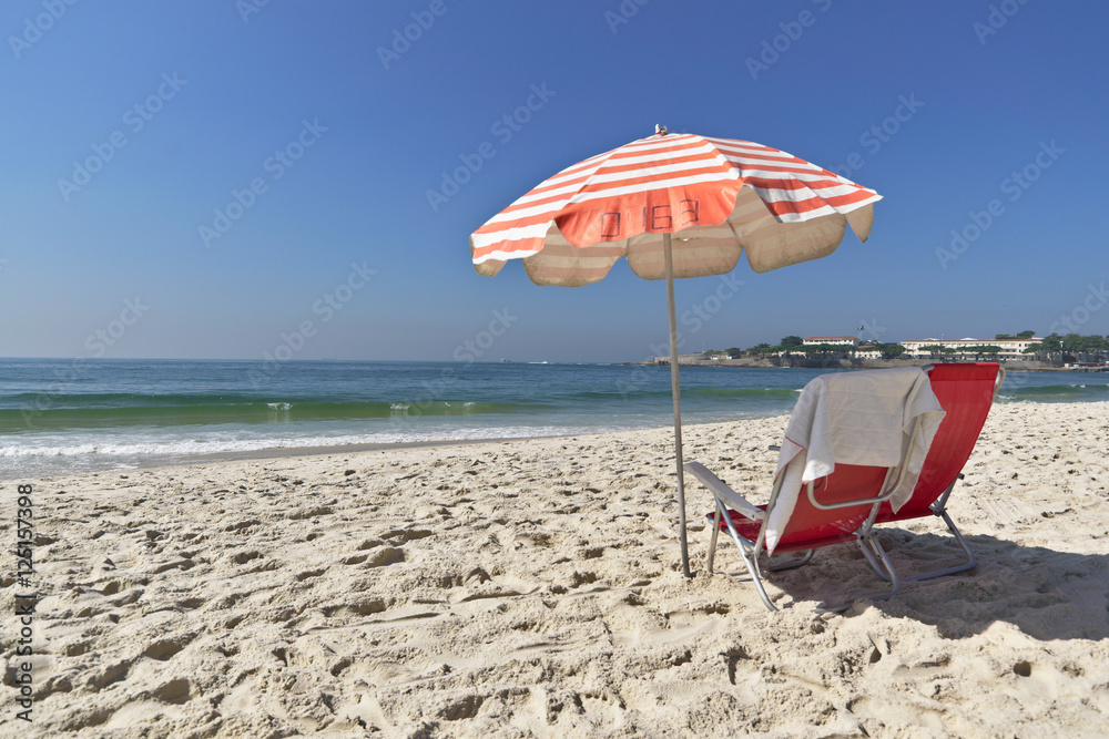 Guarda-sol e cadeiras na praia.