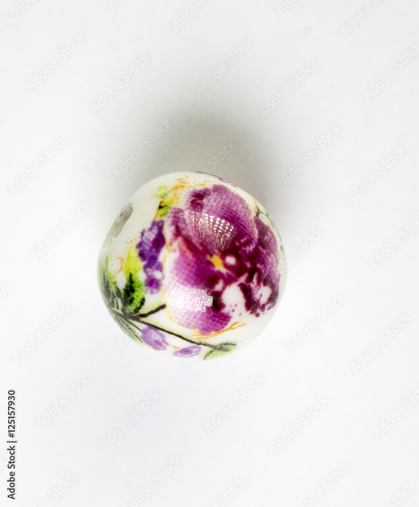 Purple isolated ceramic bead with floral design on white background 