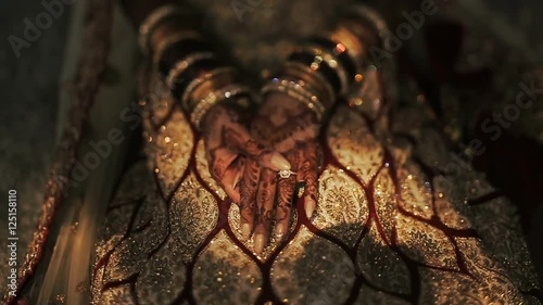 Shadows lie over the knees of Hindu bride dressed in golden clothes
