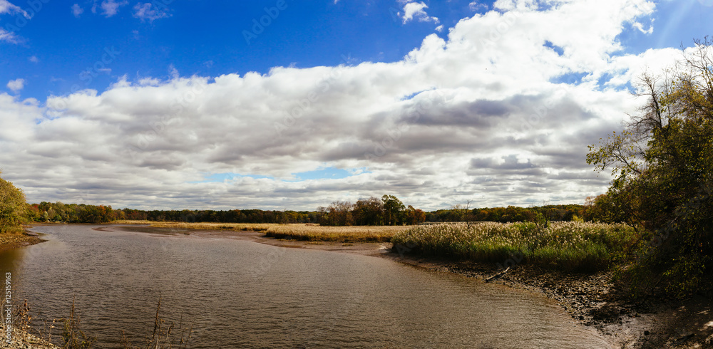 autumn landscape of river and trees without leaves blue sky  clouds on a sunny day