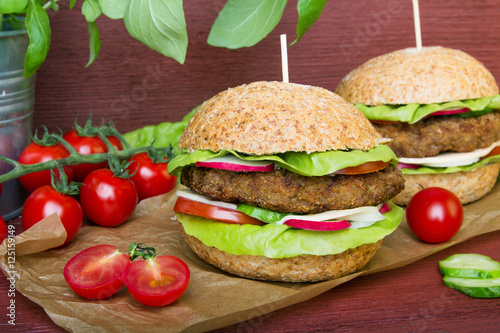 Homemade hamburgers with fresh vegetables on wooden background
