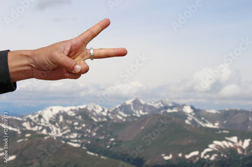 Hand showing peace sign over mountains