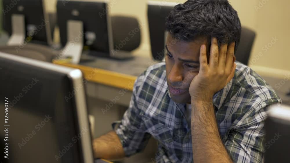 Young tired college student looking worn out while staring at the computer screen.
Young tired college student looking worn out while staring at the computer screen.