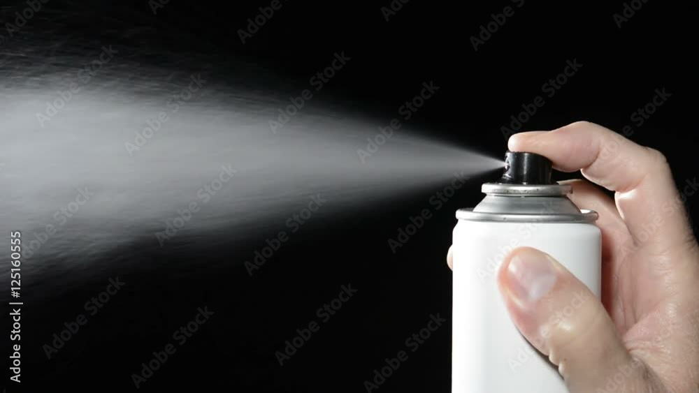 A man depresses the button on an aerosol spray can, dispensing chemicals into the atmosphere.