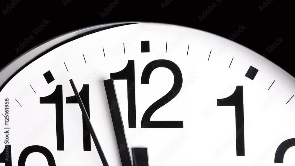 A white analog ticking clock shows the second and minute hands moving past the time integers. .