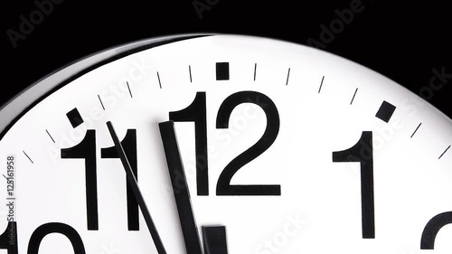 A white analog ticking clock shows the second and minute hands moving past the time integers. .
