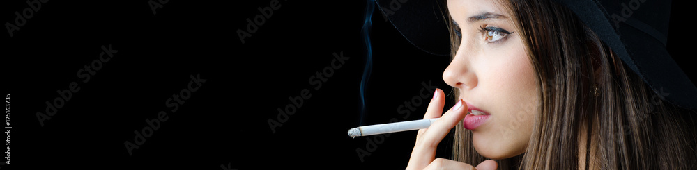 Obraz premium Portrait of the beautiful elegant girl smoking cigarette isolated on black background