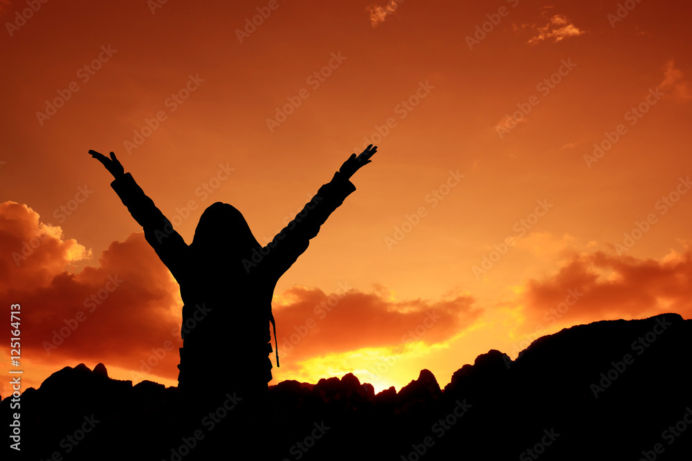 Woman raising her arms on sunset