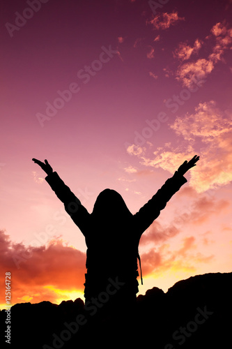 Woman raising her arms on sunset
