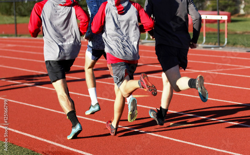 Boys group running on a track from behind