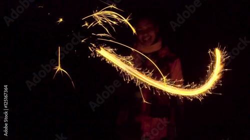 Merry black girl drawing lines in the air with sparkler photo