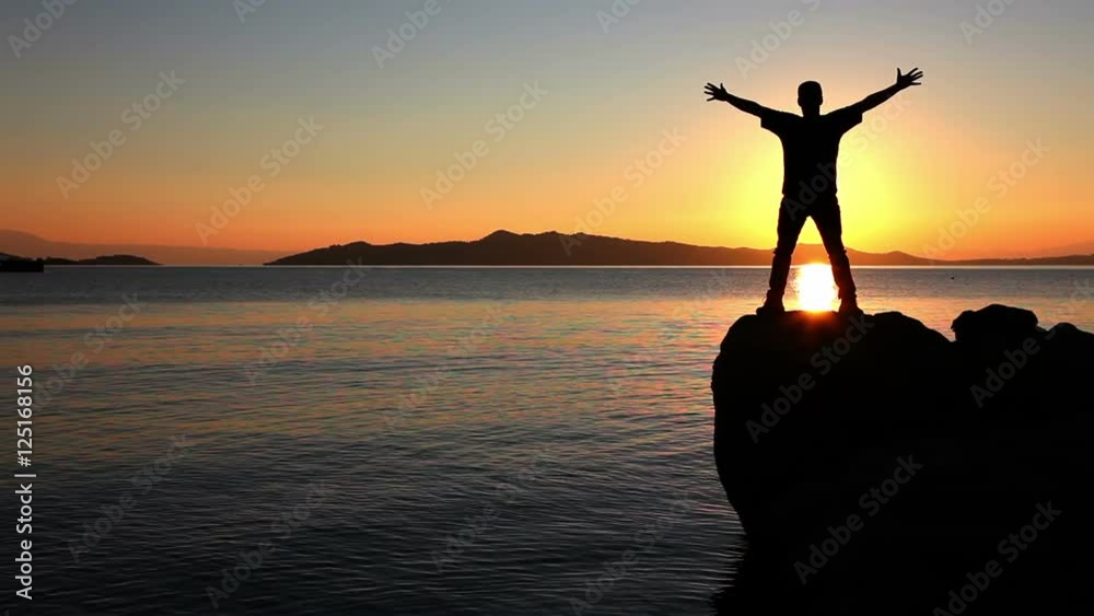 Silhouette of man exercise a yoga on the stone above a sea at sunset Silhouette of man exercise a yoga on the stone above a sea at sunset