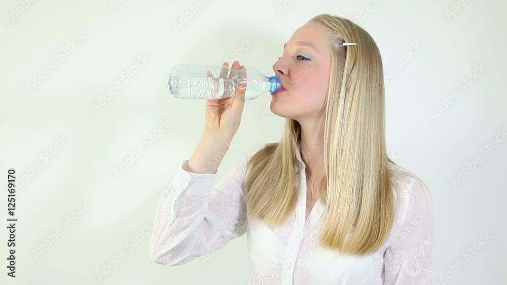 Young blonde woman drinking water from plastic bottle indoor Young blonde woman drinking water from plastic bottle indoor
