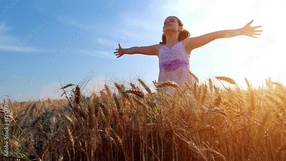 Little girl with arms outstretched in a wheat field ,sunset light.High speed camera,slow motion Little girl with arms outstretched in a wheat field ,sunset light.High speed camera,slow motion