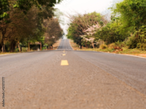 Defocus and blur image of long outback road with trees at wayside. Natural background.