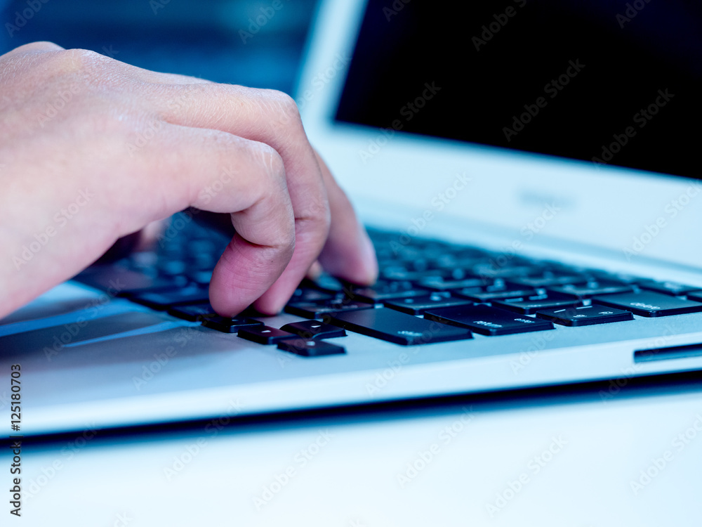 Woman hand typing on laptop keyboard. Hand with laptop typing in blue color tone. Selective focus. Woman hand typing on laptop keyboard. Hand with laptop typing in blue color tone. Selective focus.