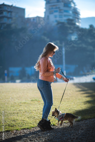 Beautiful young blond woman walks her dog in the Park