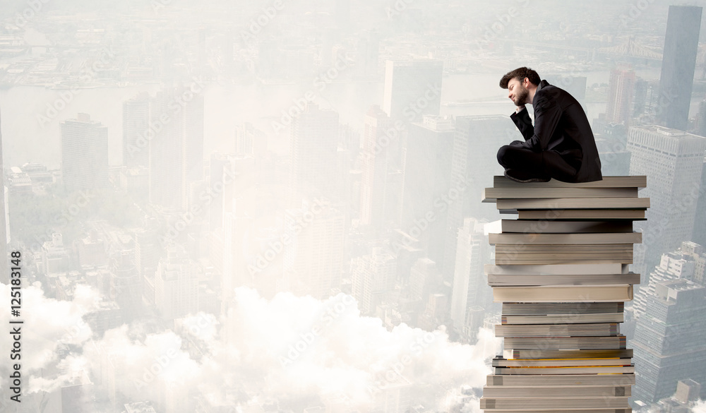 Student in city sitting on stack of books Student in city sitting on stack of books