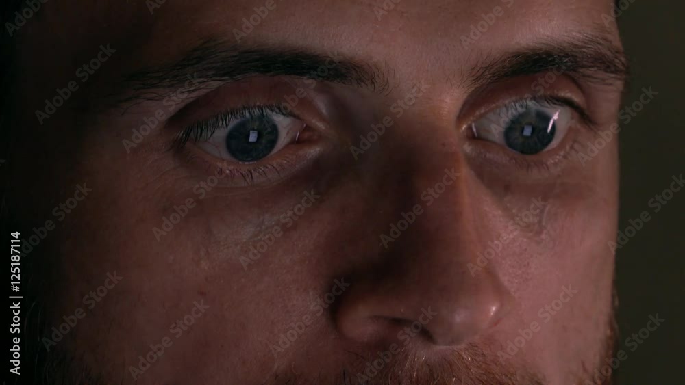 Gray eyes of focused intelligent young man using his tablet PC. Screen reflecting in the eyes, device lighting glow in the dark. 4K close up shot Gray eyes of focused intelligent young man using his tablet PC. Screen reflecting in the eyes, device lighting glow in the dark. 4K close up shot