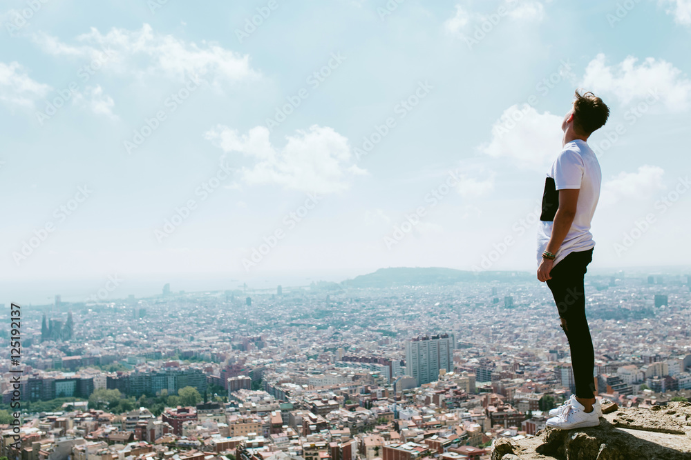 Handsome young man looking at the views form the top of a mounta Handsome young man looking at the views form the top of a mounta