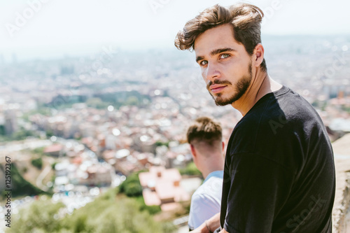 Photography Two young men looking at the views form the top of a mountain.