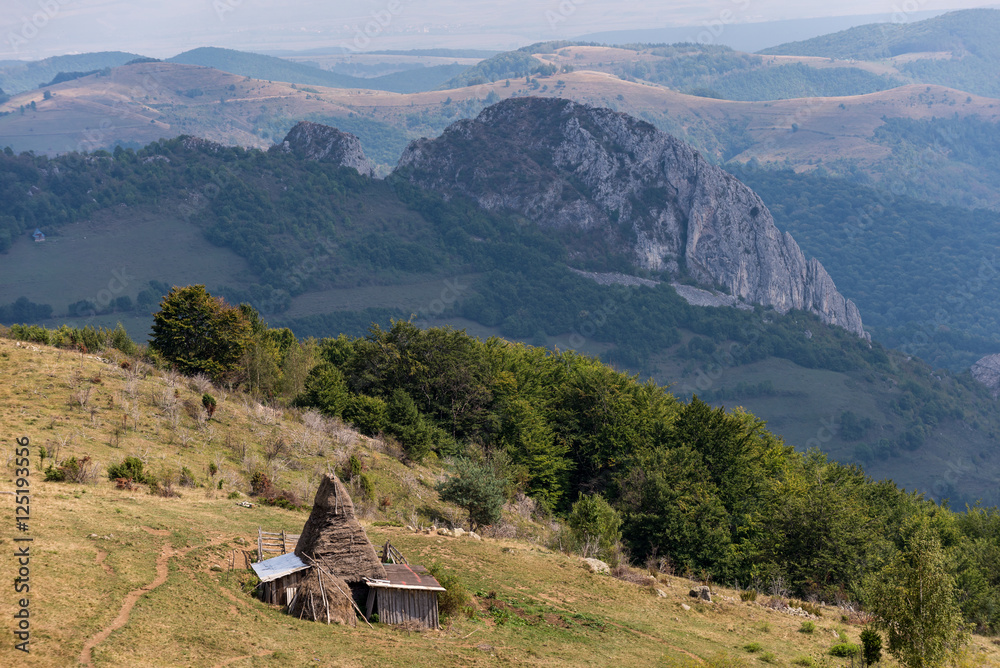 Amazing Romanian countryside in mountains with a haystack in the summer afternoon
