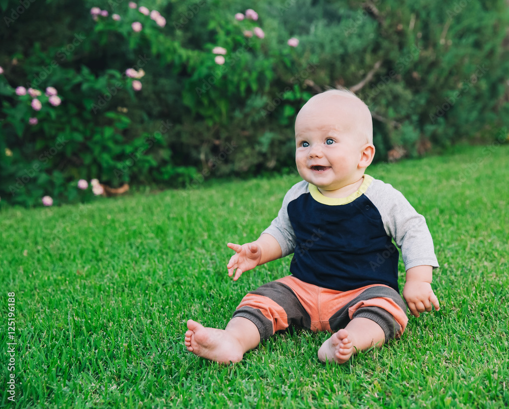 Happy adorable baby boy sitting on the grass Happy adorable baby boy sitting on the grass