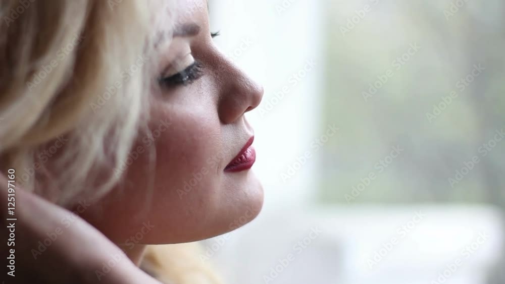 Portrait of beautiful young women near the window smiling and corrects hairstyle Portrait of beautiful young women near the window smiling and corrects hairstyle