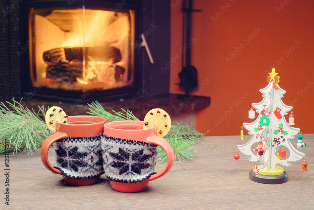 Cup with Christmas ornament near fireplace. Winter holiday concept