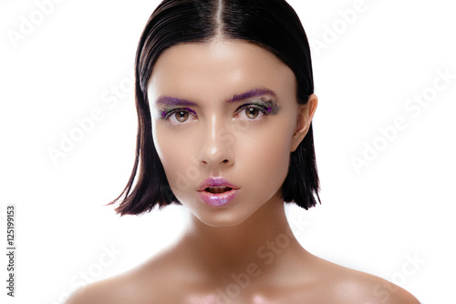 Beautiful woman model with shiny skin posing on a white background. The brunette with wet hair and a gentle colorful makeup.