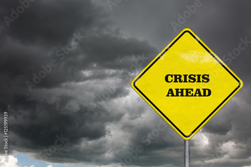 A crisis ahead road sign on a dramatic sky background