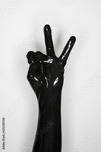 gesture of a hand wearing a black latex glove, victory sign