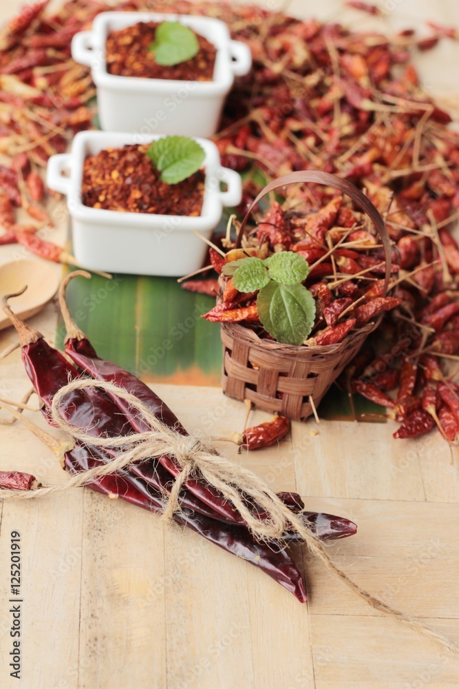 Chili powder and dried peppers on wood background.