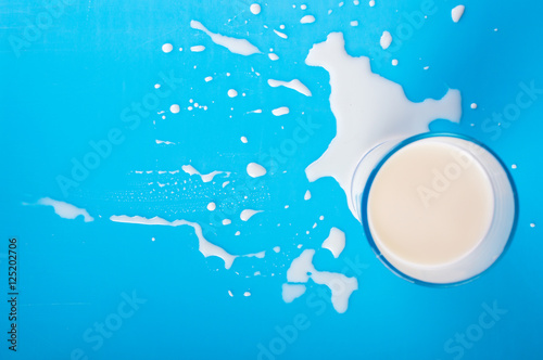 Drip of milk, a glass of milk. on a blue background.Top view. Flat lay.