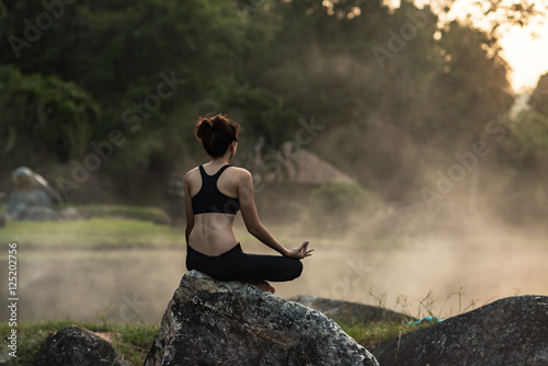 Young girl doing yoga fitness exercise outdoor in beautiful landscape. Morning sunrise,Silhouette of a beautiful Yoga woman in the morning at the hot spring park, soft and select focus