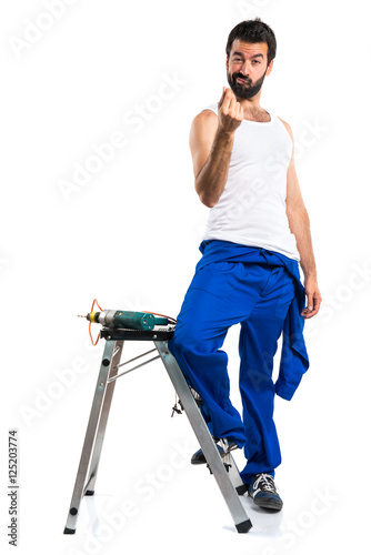 Young electrical technician with a drill making money gesture