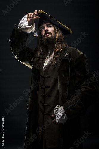 Portrait of a medieval bearded pirate on black background.
