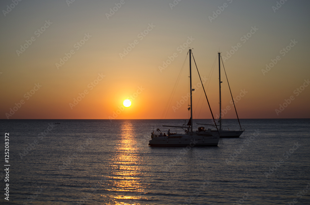 Silhouettes of yachts in the sea at sunset