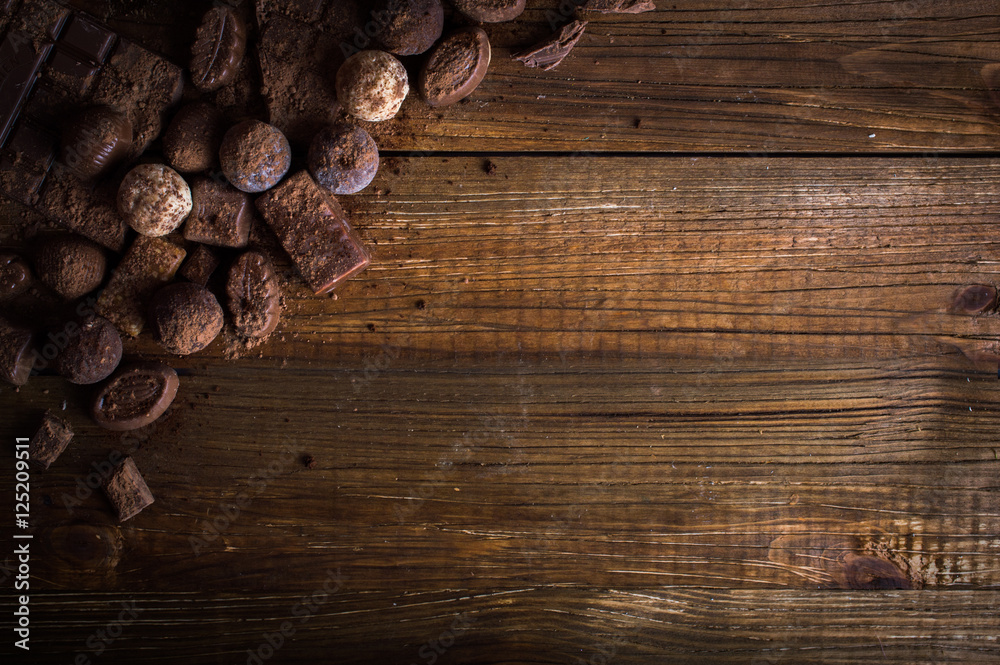Naklejka premium chocolate candy in cocoa on a wooden table
