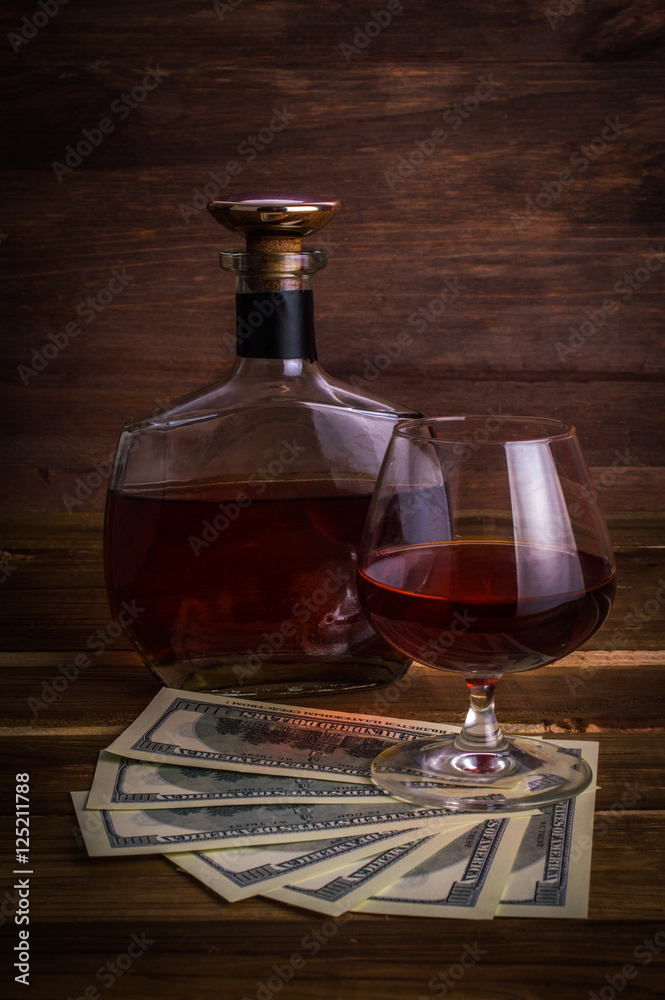 Glass of whiskey with money on a wooden table. Glass of whiskey with money on a wooden table.