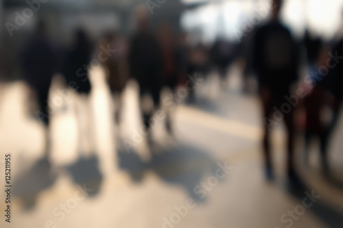 Blurred image of people dark silhouettes moving at city street. Art toning abstract urban background