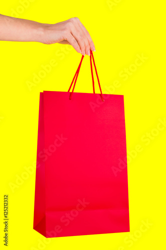 Hand with red bag on a yellow background