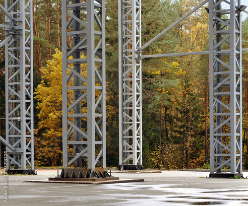 Modern metal support columns on background of autumn forest.
