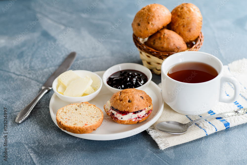 Scones with butter and jam with tea on the table Scones with butter and jam with tea on the table