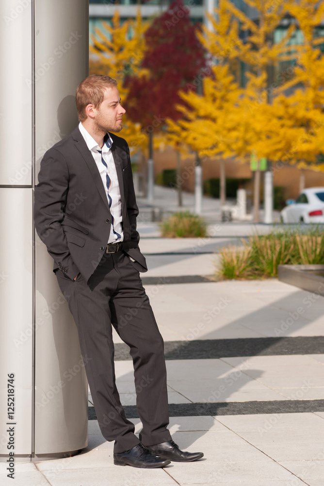 Standing businessman in suit in front of office park. man in suit in front of entrance door Standing businessman in suit in front of office park. man in suit in front of entrance door