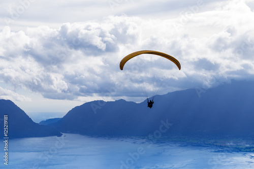 Paraglider flying over mountains in summer day