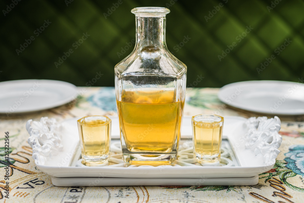 Carafe with honey vodka on white elegant tray Carafe with honey vodka on white elegant tray