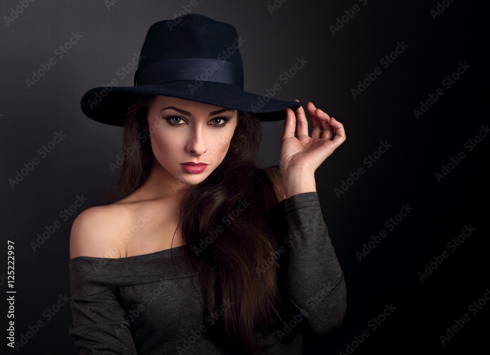 Elegant makeup woman in fashion hat posing on dark shadow backgr Elegant makeup woman in fashion hat posing on dark shadow backgr