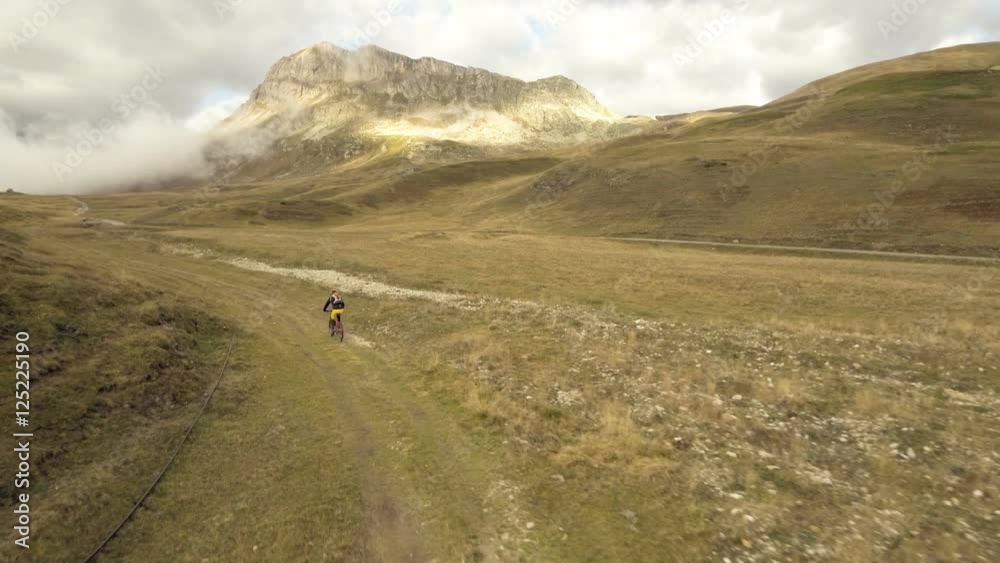 Aerial shot of mountain biker riding a grass covered trail on alpine pass in autumn season
Aerial shot of mountain biker riding a grass covered trail on alpine pass in autumn season