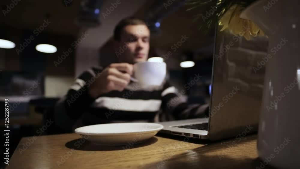 Handsome man working on laptop and drink coffee in cafe Handsome man working on laptop and drink coffee in cafe